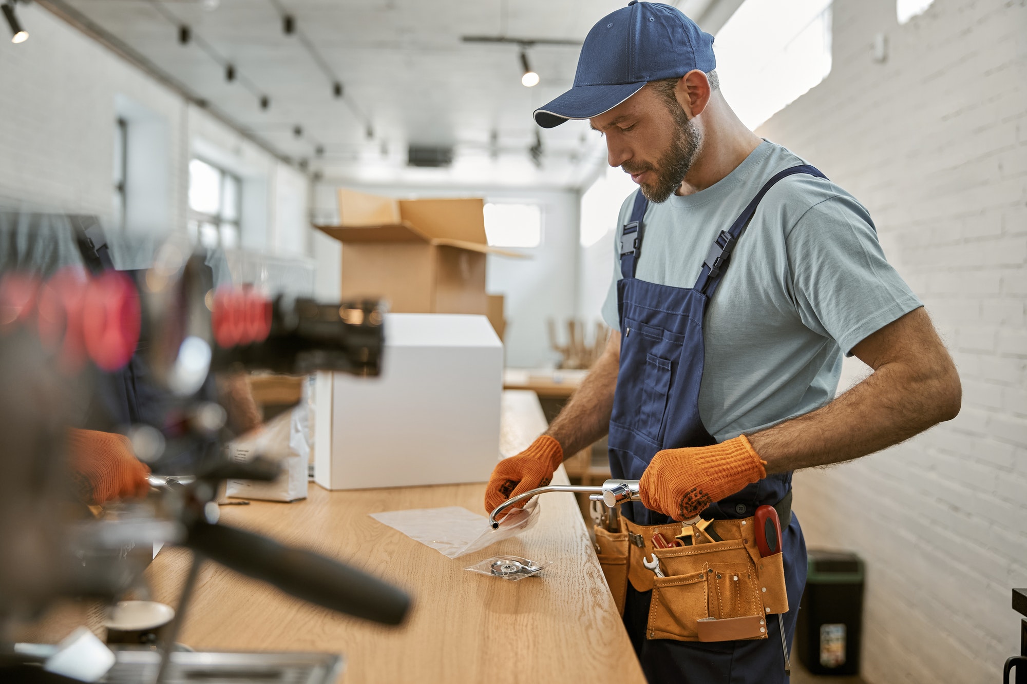 Bearded young man holding metal coffee machine tap